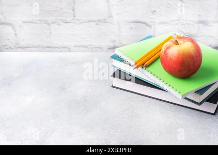 A fresh red apple on a stack of books and notebooks. The concept of a school breakfast snack Copy space, Stock Photo