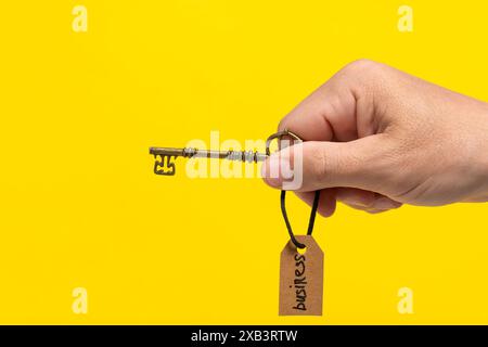 Hand with key and tag on it with inscription business. Concept of success Stock Photo
