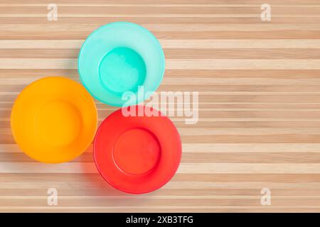Three different colored plastic empty bowl on wooden table. Top view Stock Photo