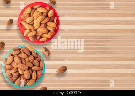 California almonds in two small bowls isolated on wooden table. top view Stock Photo