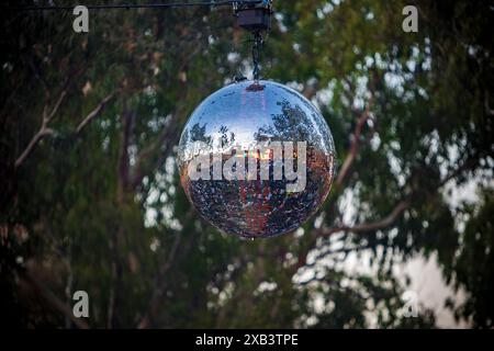 View of a disco ball hanging on a festival stage located in a forest Stock Photo