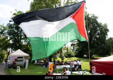 Leipzig, Germany. 10th June, 2024. A Palestinian flag flies in a pro-Palestinian camp in a park in Leipzig. Around 40 young activists have set up several tents and information stands. The camp is to be held for several weeks with lectures, discussions and cultural events. The police confirmed a registered assembly under the motto: 'Defamation of Palestinian solidarity' until June 24. Credit: Hendrik Schmidt/dpa/Alamy Live News Stock Photo