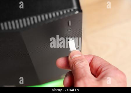 USB cable plug connecting by the user hand to an computer close up. Daily office routine concept Stock Photo