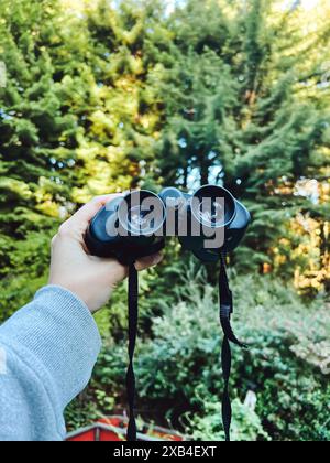 Female hand holding a binocular outdoors, close-up view, exploring the nature concept Stock Photo