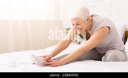 Senior Woman in Sportswear Stretching Her Legs on Bright Morning Stock Photo