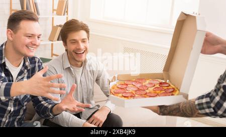 Friends taking slices of hot pizza from delivery box Stock Photo