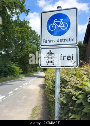 Traffic sign Bicycle road underneath sign with pictogram for cars motorbikes free, left at the edge of the picture in the middle of road marking on Stock Photo