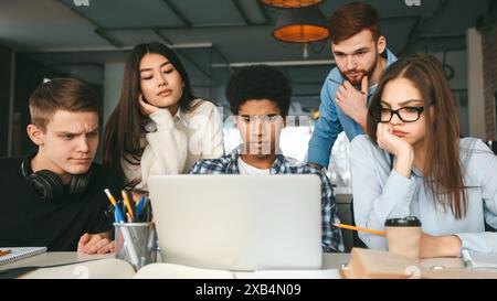 Smart serious students working on project in front of laptop Stock Photo
