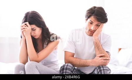 Couple Sitting on Bed With Sad Expressions Stock Photo