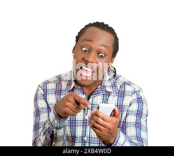 portrait of a displeased, angry, mad young man, not happy by what he sees on cell phone, isolated on white background. Stock Photo