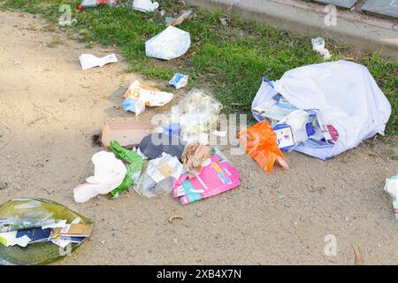 Close up of trash bags thrown and open on street next to trash and recycling bins. Vandalism and incivility of people. Stock Photo
