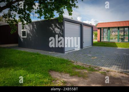 Anewly built double garage with roller doors stands under a tree Stock Photo
