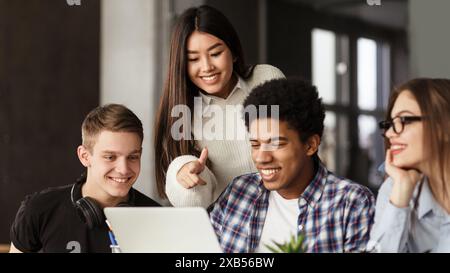 College students using laptop in library, studying together Stock Photo