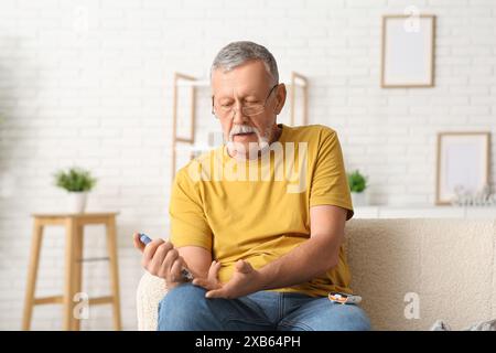 Senior man giving himself insulin injection at home. Diabetes concept Stock Photo