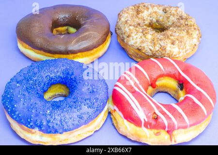 Four donuts with a different topping laying down on a blue background. Stock Photo