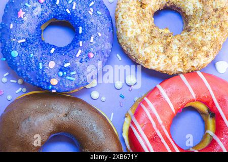 Four donuts with a different topping laying down on a blue background. Stock Photo