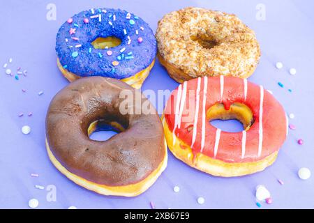 Four donuts with a different topping laying down on a blue background. Stock Photo