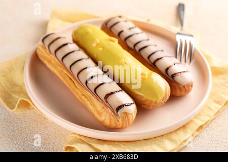 Different tasty glazed eclairs served on color textured table, closeup Stock Photo