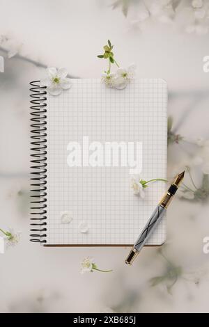 Guest list. Notebook, pencil and beautiful cherry tree blossoms on spring floral background, flat lay Stock Photo
