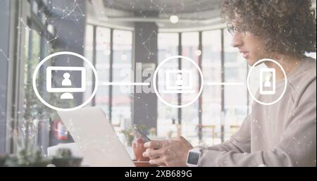 Young biracial male using smartphone and laptop in modern cafe Stock Photo