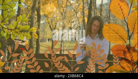 Young Caucasian man sitting on bench holding a coffee cup in park Stock Photo