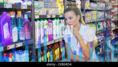 Caucasian woman thoughtfully looking at products on supermarket shelf Stock Photo