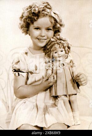 Child star Shirley Temple holding a doll in her likeness. The doll released in 1934 quickly became the bestselling doll. Stock Photo