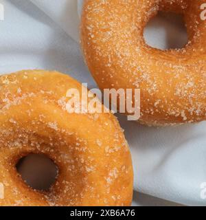 Close-up of two vanilla sugar donuts on a white tablecloth, no people Stock Photo