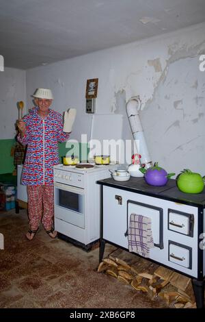 mature male british expat in appropriate clothing fooling around while cooking meal in his kitchen for fellow expats zala county hungary Stock Photo