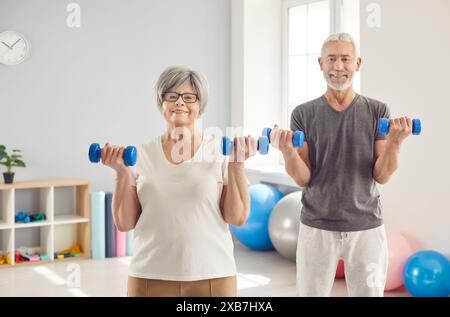 Senior people wearing sportswear doing fit sport exercises with dumbbells in gym together. Stock Photo