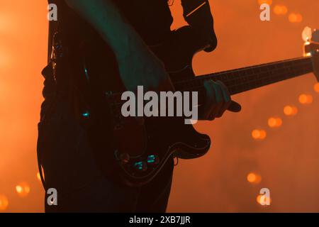 Electric bass guitar player silhouette in bright stage lights, closeup photo with selective focus Stock Photo
