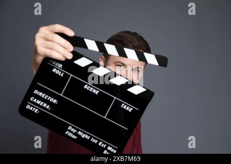 Making movie. Man with clapperboard on grey background Stock Photo