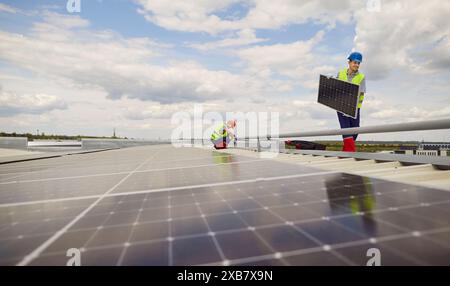 Workers Installing Or Maintaining Solar Panels On Roof Stock Photo