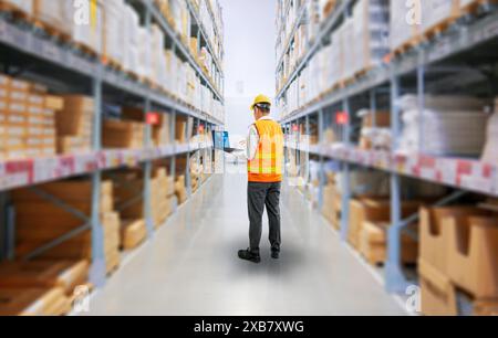 Asian worker or engineer in warehouse with stack of cardboard boxes Stock Photo