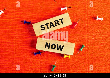 Business and Start now concept. Copy space. Start now symbol conceptual words on the wooden blocks . Beautiful orange background Stock Photo