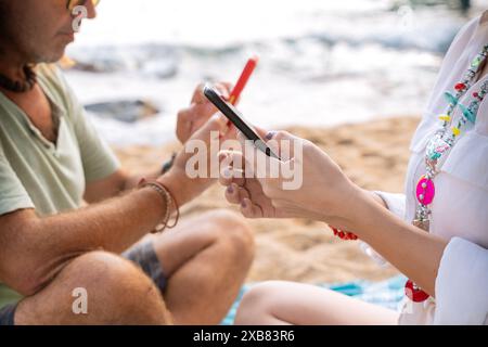 Unrecognizable couple on the beach browsing smartphones apps. Stock Photo