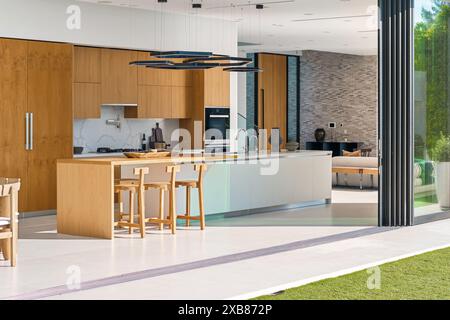 A Modern kitchen with an island table and bar stools Stock Photo