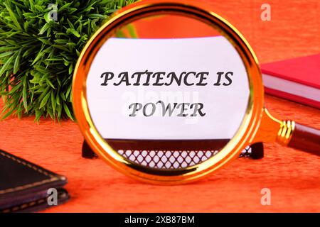 Concept words PATIENCE IS POWER through a magnifying glass on a white business card Stock Photo