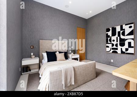 A modern bedroom featuring a spacious bed and wall art Stock Photo