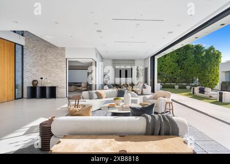 A White spacious living room in a luxurious house connected to a large outdoor patio area Stock Photo