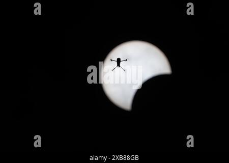 Silhouetted man flying in dark sky with sun backdrop Stock Photo