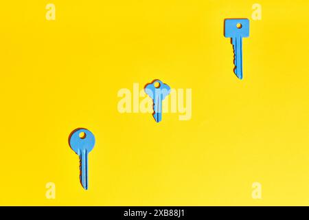 Blue keys on vibrant yellow background. Flat lay Stock Photo
