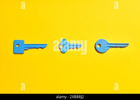 Blue keys on vibrant yellow background. Flat lay Stock Photo