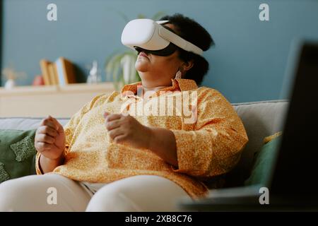 Retired African American elderly woman playing video game using VR goggle and experiencing car drive in virtual reality Stock Photo