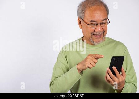 Portrait smiling Asian older man smiling and pointing at his cell phone studio shot isolated on Stock Photo