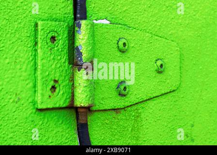 A close-up of a rusted green hinge on a building Stock Photo