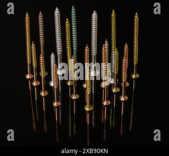 A variety of colorful and sized screws on a reflective surface. Stock Photo