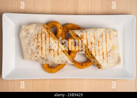 A plate with a chicken wrap and onion rings Stock Photo