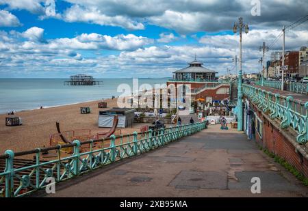 A view from the promenade down to the beach with Shelter Hall restaurant and the ruins of the old West Pier, Brighton, East Sussex, UK Stock Photo