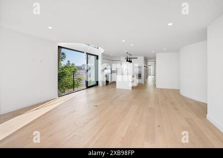 A spacious living room with hardwood floors and glass doors opening to the yard. California, USA Stock Photo